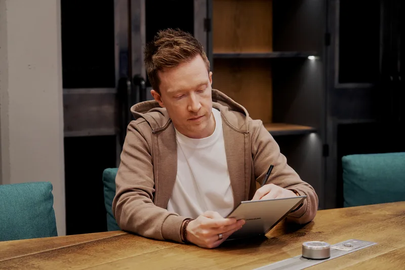 Olly Richards, business coach for online education entrepreneurs, writing notes at his desk